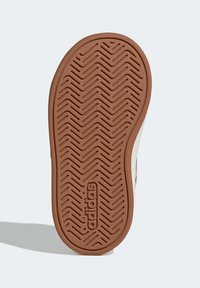 Suola di scarpa in gomma marrone con motivo a zigzag, con logo "adidas" inciso al centro. Design pulito e piatto senza accenti aggiuntivi.