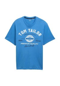 T-shirt bleu à manches courtes Tom Tailor avec un texte blanc et noir indiquant "Tom Tailor Original Supplies since 1962 Premium Quality Essentials."