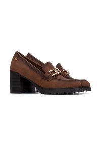 Mocasines de piel marrón con tacón bloque grueso y detalles en metal dorado. Suela negra texturizada y parte superior lisa con acentos de costura.