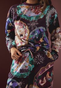 Lange Schlafanzugset mit einem dunkelvioletten Muster, das Tiere, Schneeflocken und geometrische Designs zeigt. Mit elastischem Bund und Kordelzug-Detail.