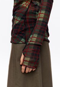 Dopasowana bluzka z długim rękawem w zielono-czarną kratę, wykonana z lekkiego materiału. Rękawy wyposażone w otwory na kciuki.