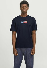 Marineblå bomulds T-shirt med et brystmotiv med "JACK & JONES" i rød og blå på en hvid baggrund; korte ærmer, regular fit.
