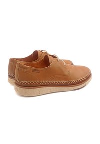 Chaussures en cuir tan avec une surface lisse, bout rond et semelle texturée beige. Présente des coutures décoratives le long du bord et un système de laçage.