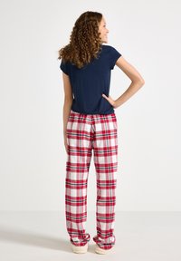 Navy short-sleeve top paired with plaid flannel pajama pants in white, red, and gray. The pants feature an elastic waistband and relaxed fit.