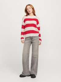 Pull en tricot rayé rouge et blanc avec des manches longues, un col rond et une coupe décontractée, associé à un jean large taille haute gris.