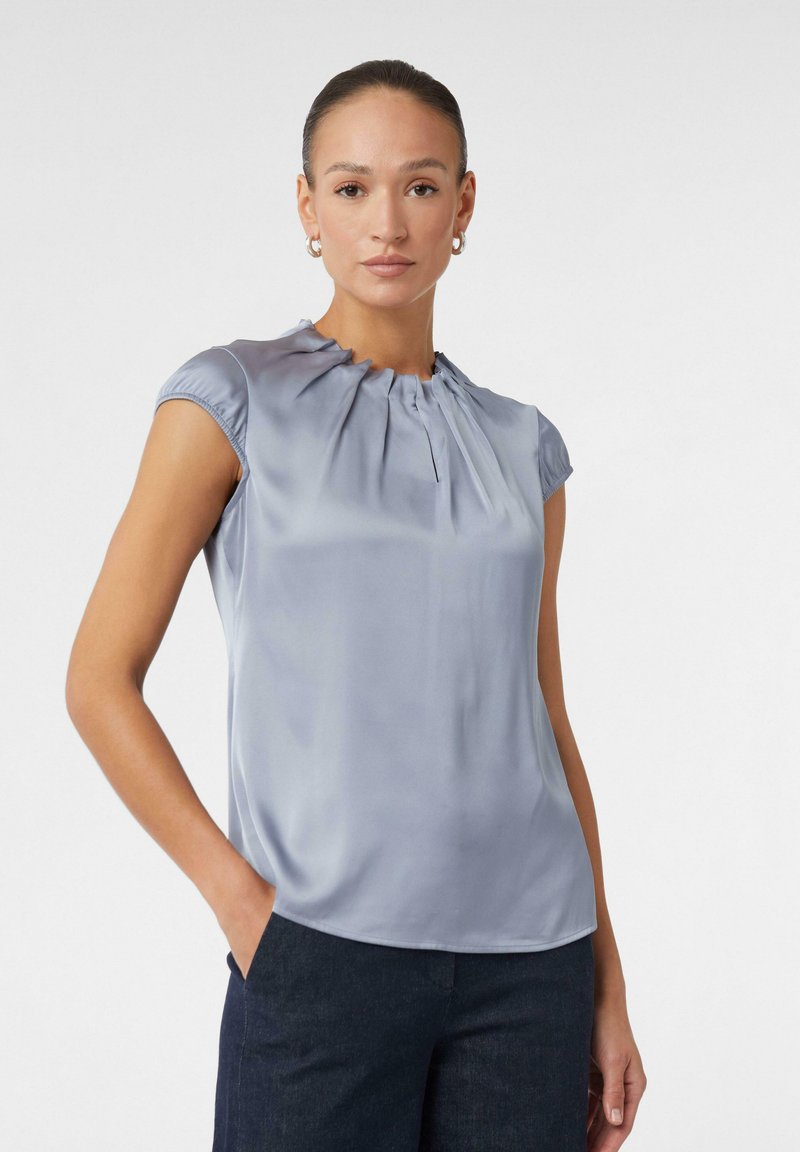 Himmelbluse mit kurzen Ärmeln aus Satin, mit gerafftem Ausschnitt und glatter Textur. Taillierte Passform mit abgerundetem Saum.