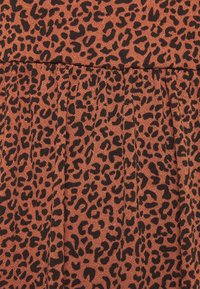 Leopardikuvioista kangasta ruosteenruskeana mustilla täplillä, jossa laskokset. Pehmeä tuntuma ja kudottu ulkonäkö. Suorakaiteen muotoinen.