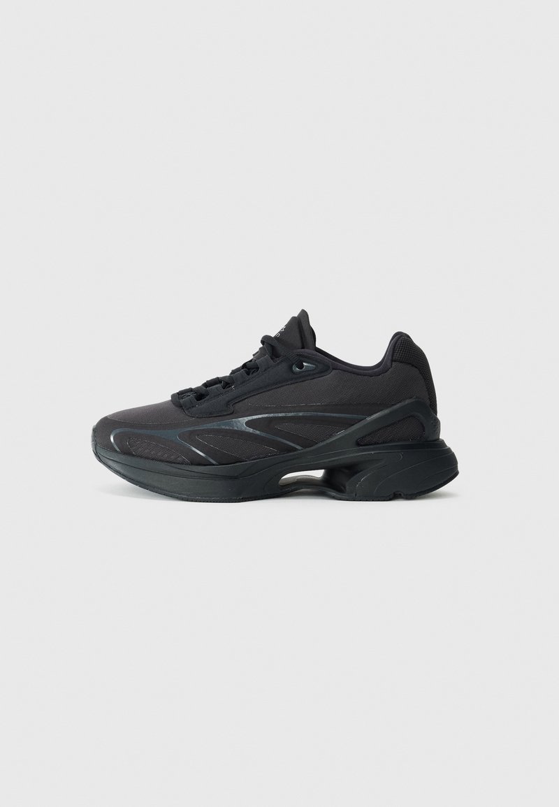 Baskets de sport noires avec semelle épaisse, dessus en mesh et design à lacets, vues du côté extérieur sur un fond uni.