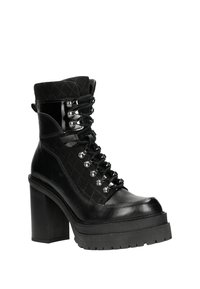 Stivaletto nero con tomaia in tessuto trapuntato, lacci frontali, occhielli in argento, tacco grosso e suola piatta. Accenti in pelle liscia.