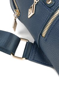 Marineblaues genarbtes Lederhandtasche mit goldenen Reißverschlüssen und Beschlägen, ausgestattet mit einem strukturierten Riemen und dekorativen Charms. Nahaufnahme der Riemenbefestigung.