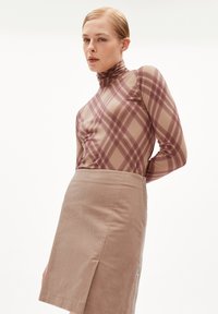 Langsleeve top in lichtbeige met een bruine geruit patroon, gecombineerd met een gestructureerde beige rok. Beide items hebben een getailleerd ontwerp.