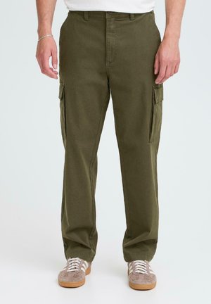 Cargo pants in olive green fabric with a relaxed fit, featuring side cargo pockets and a smooth texture. Worn with light brown sneakers.