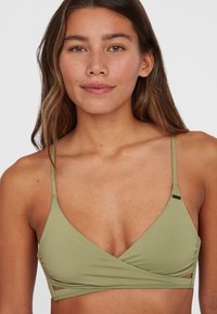 Olivgrön bralette med v-ringning och tunna band. Har en omslagdesign med utskärningar och en liten metallaccent. Slät textur.