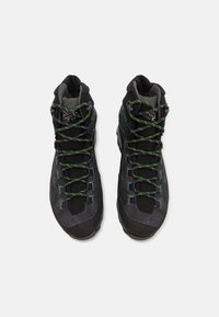 Bottes de randonnée noires avec un design texturé, présentant des lacets verts et jaunes, une forme ergonomique et des semelles en caoutchouc pour une meilleure adhérence.