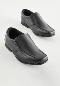 Zapatos de cuero negro con un diseño sin cordones, textura suave y puntera redondeada. Detalles cosidos y tacones bajos apilados.