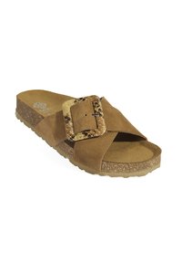 Sandale glissante en suède marron avec un design à lanières croisées, semelle beige texturée, et une boucle décorative présentant un motif en peau de serpent.