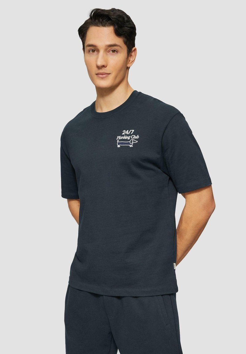 Navyblauwe katoenen T-shirt met korte mouwen, voorzien van een witte bedrukte opdruk met de tekst "24/7 Planking Club" op de borst.