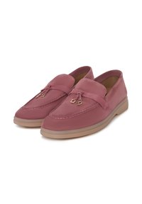 Paire de mocassins en daim rose poussiéreux avec bouts arrondis, pampilles décoratives et semelles en caoutchouc beige clair sur fond blanc.