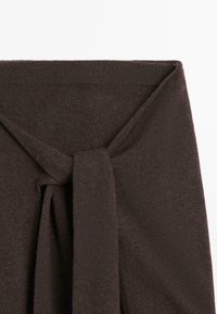 Brown knitted garment with a tied waist detail, featuring a soft texture and a smooth finish, no visible patterns or hardware.