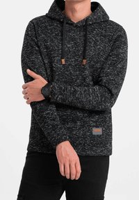 Černá a šedá mikina s dlouhými rukávy, šňůrkami a hnědými akcenty. S visačkou na pravé dolní straně. Měkká textura.