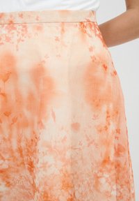 Luftiger, oranger Blumenkleid aus leichtem, transparentem Stoff mit sanften Texturen; weist einen subtilen Farbverlauf und zarte botanische Muster auf.