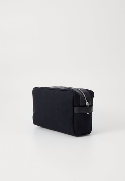 Svart lerret kosmetisk veske med rektangulær form, kontrasterende lær glidelås, og et stilrent design. Glatt tekstur, minimalistisk stil.