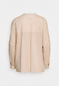 Camicia di lino beige chiaro con vestibilità rilassata, scollo rotondo, schiena arricciata e maniche lunghe con polsini abbottonati.