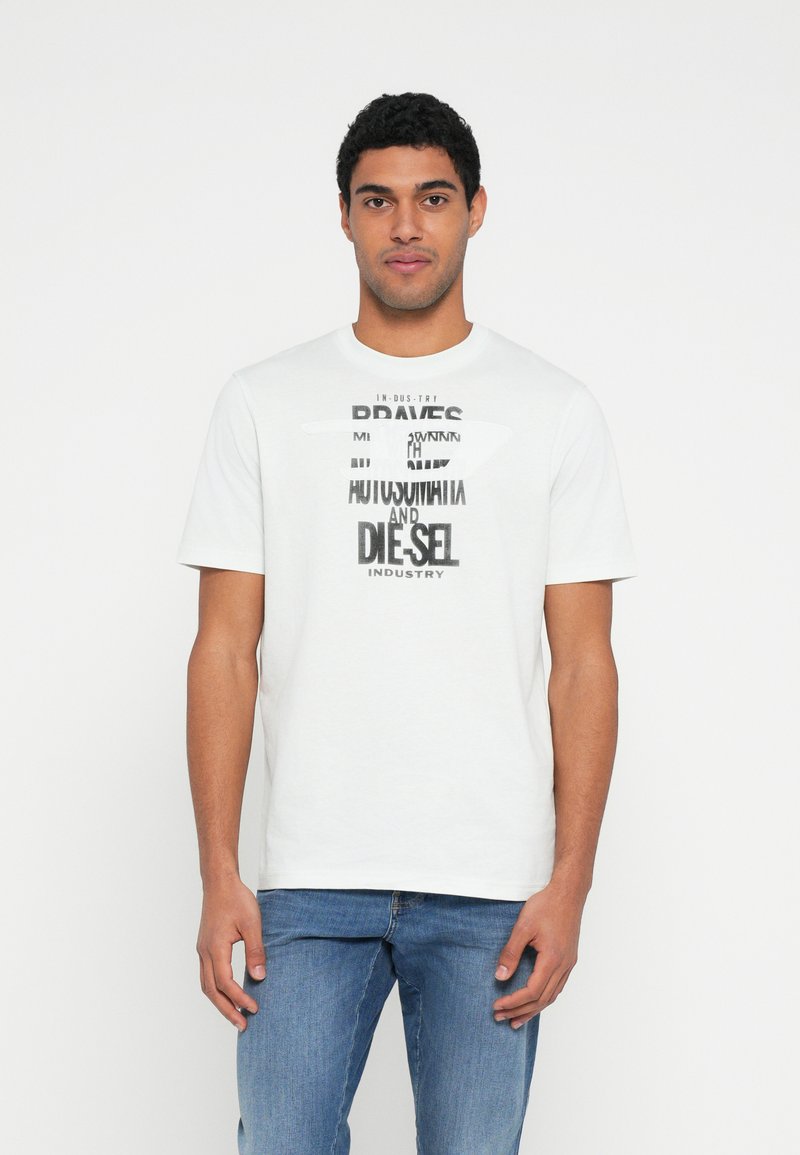 White short-sleeve t-shirt featuring bold black text graphics in varying fonts, complemented by a round neckline and casual fit, worn with jeans.