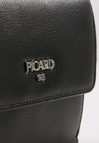 Zwarte leren tas met een gestructureerd oppervlak, een zilveren logo met de tekst "PICARD 1928" en gestikte accenten langs de randen.