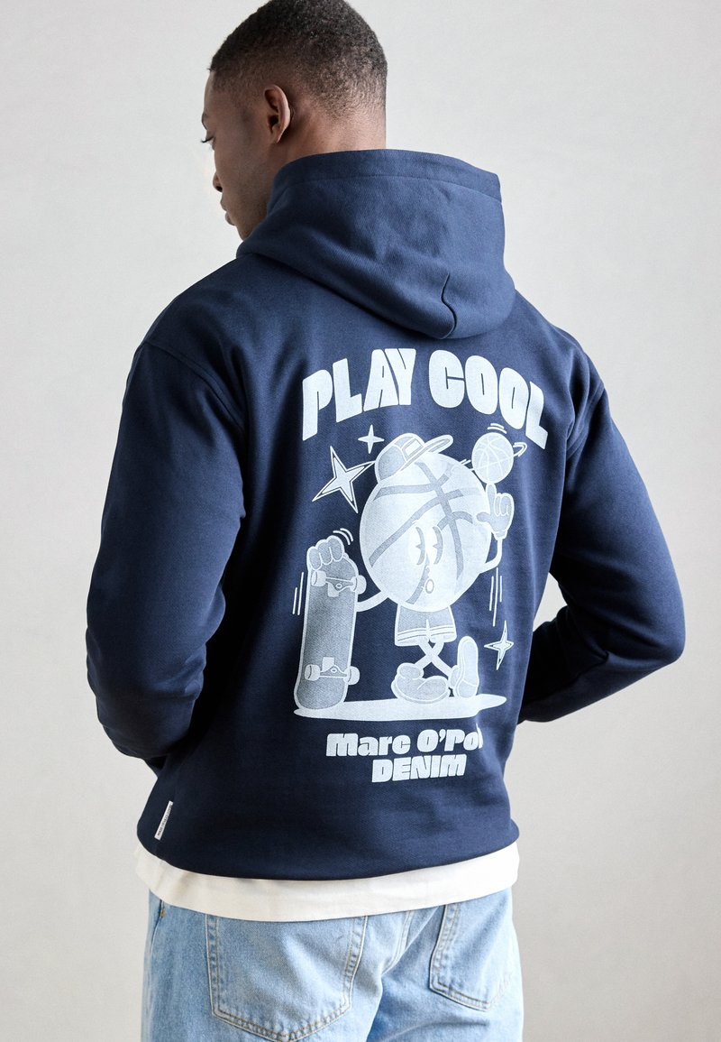 Hanorac bleu marin cu glugă ajustabilă, având o grafică albă pe spate cu un personaj de desen animat care face skateboard și textul "PLAY COOL."