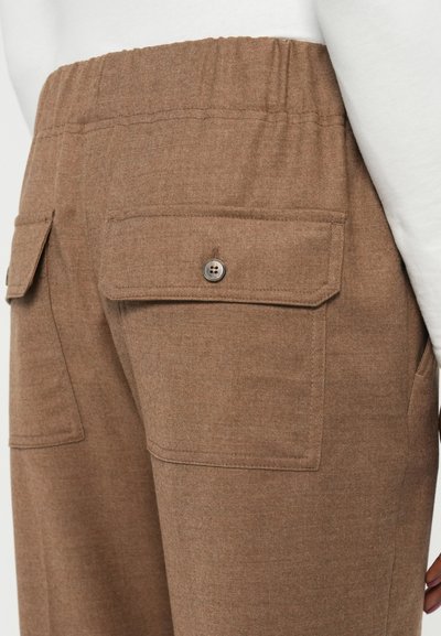 Pantaloni din țesătură maro, cu un elastic la talie, două buzunare la spate cu închidere cu buton și o textură moale.