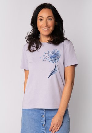 T-shirt en coton lavande clair à manches courtes, avec un motif de pissenlit bleu sur le devant. Texture lisse et coupe décontractée.