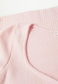 Helles rotes Sweater mit einem gerippten Kragen, weichem Material und rundem Halsausschnitt, aus glattem Stoff und mit minimal sichtbaren Nähten.