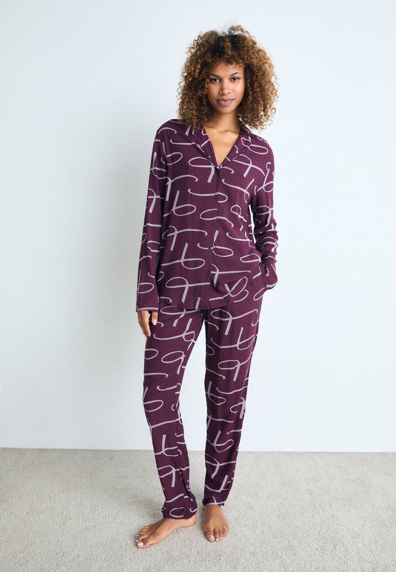 Conjunto de pijama burdeos con patrones abstractos blancos, que incluye una camisa abotonada con cuello tipo notch y mangas largas, combinada con pantalones a juego.