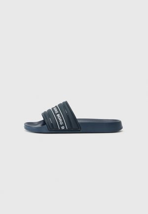 Modra drsna sandal s teksturiranim trakom s tremi utori in belim napisom. Ravno podplat in minimalistična zasnova. Narejena iz sintetičnega materiala.