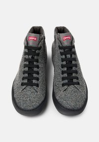 Szare wełniane sneakersy z czarnymi sznurówkami, niskoprofilowy design, okrągły czubek i subtelna tekstura. Na językach znajduje się czerwone logo Camper.