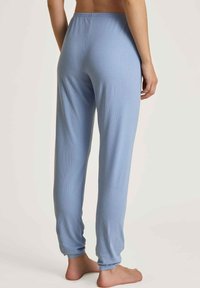 Lichtblauwe geribbelde pyjamabroeken hebben een relaxte pasvorm, een elastische tailleband en taps toelopende boorden, gemaakt van een zachte stof voor comfort.