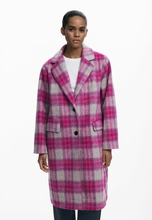 Manteau oversize en mélange de laine avec un motif tartan rose et gris, grands revers, fermeture à boutons sur le devant et deux poches latérales.