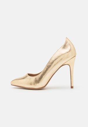 Guld metalisk spids tå højhælet sko med slank stiletthæl, glat tekstur og lavtskårede sider på hvid baggrund.