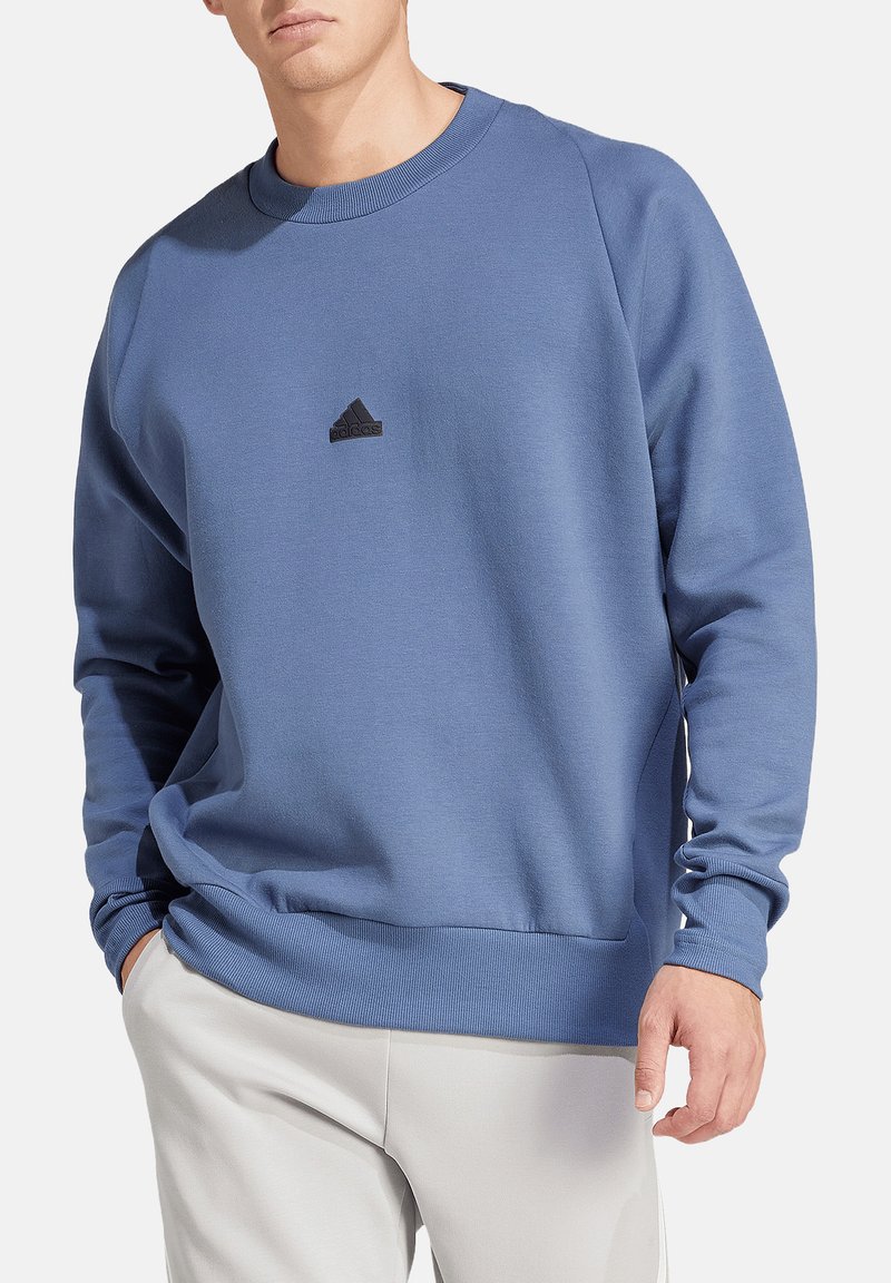 Felpa blu realizzata in tessuto morbido, con collo a girocollo, polsini a costine e un logo Adidas nero sul petto.