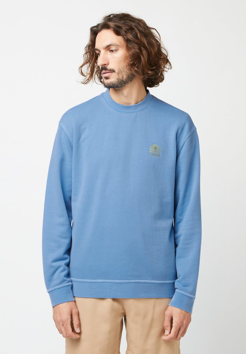 Lichte blauwe pullover sweatshirt met een geribde ronde hals en lange mouwen. Opvallend geborduurd logo op de borst in het groen. Gladde textuur.