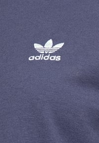 Námořnická modrá bavlněná tričko s bílým vyšívaným logem Adidas trefoil na hrudi, s hladkým, mírně texturovaným materiálem.