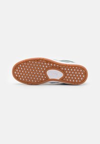 Fehér sneaker talp narancssárga gumi tapossal, amely enyhén struktúrált gyémántmintázattal rendelkezik, és a közepén a "VANS" logó található.