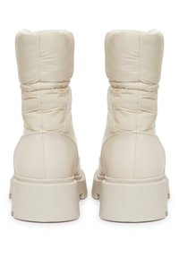 Beżowe botki w stylu puchowym o gładkiej fakturze, wysokim wyściółkowanym cholewce i masywnych gumowych podeszwach. Charakteryzują się bezszwowym wzornictwem i minimalnymi akcentami.