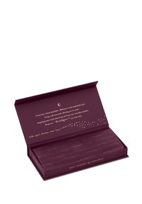 Głęboki fioletowy pudełko z wytłoczonym złotem wzorem i tekstem. Wewnątrz znajduje się jedwabna maska na oczy, ozdobiona powtarzającymi się wzorami nazwy marki.