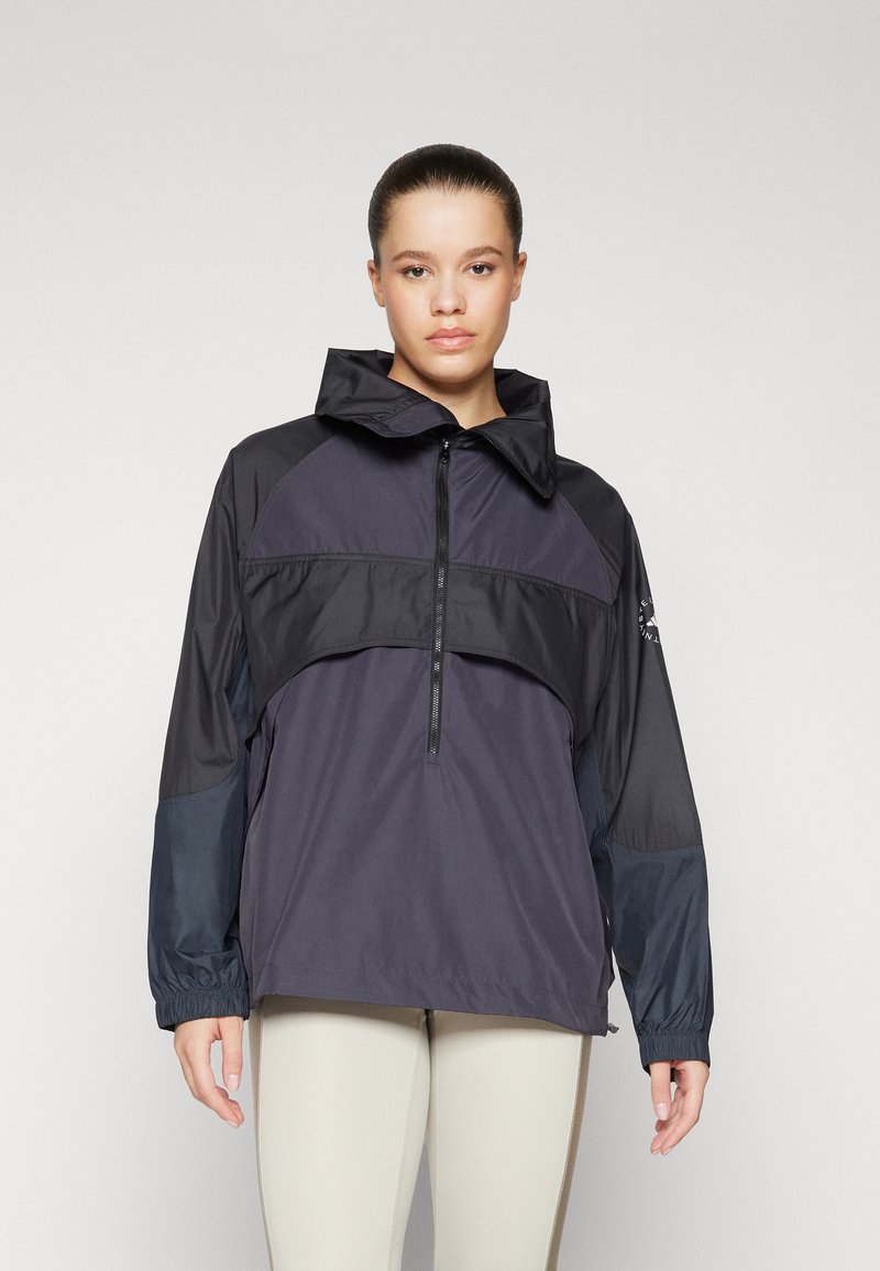 Veste légère noire et marine avec un zip partiel, un col haut et des poignets élastiques ; présente un design coloré et une texture lisse.