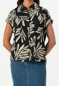 Czarna bluzka z krótkim rękawem z motywem liści w kolorze kremowym i jasnoniebieskim. Zapięcie na guziki z kołnierzykiem i luźny krój.