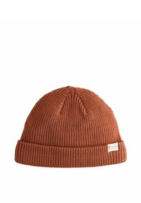Bonnet en tricot couleur rouille avec une texture côtelée, présentant un revers replié et une petite étiquette cousue sur le côté.