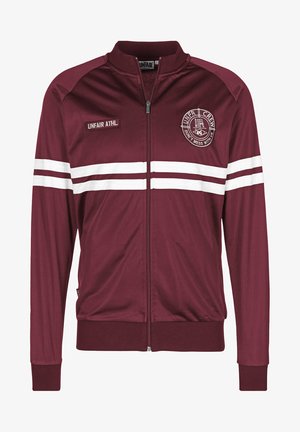 Maroon zip-up jacket made from smooth fabric. Features white stripes and embroidery on the chest, along with ribbed cuffs and hem.