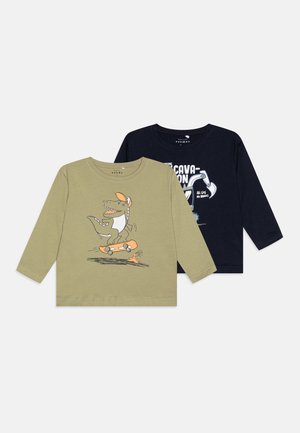 Două tricouri cu mânecă lungă: unul verde măsliniu cu un dinosaur pe o placă de skate, celălalt bleumarin cu un design grafic de text. Material din bumbac.